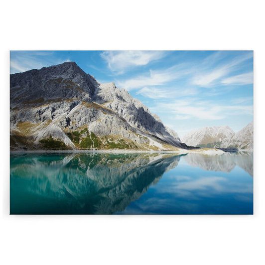 Leinwandbild Bergsee bei klarem Wasser – Blaues Wasser & Graue Berge – 120 cm x 80 cm